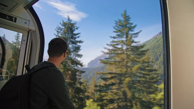 Portrait of a tourist man traveling on Bernina Express panoramic train with a stunning view of the Alps. Perfect for lifestyle, travel, vacation, and adventure in the Swiss Alps