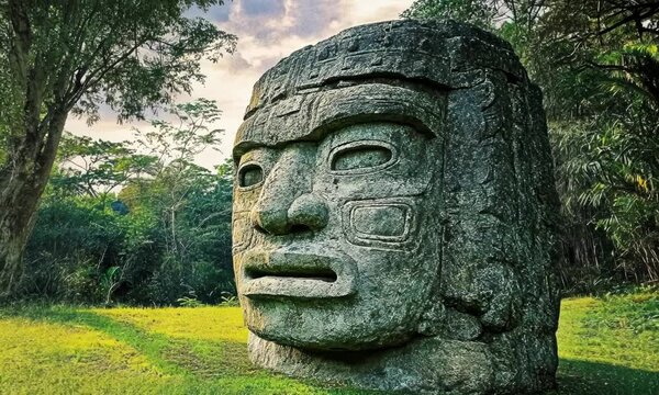 Giant Olmec head sculpture in jungle, travel and culture concept