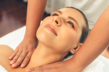 Naklejka premium Caucasian woman customer enjoying relaxing anti-stress spa massage and pampering with beauty skin recreation leisure in day light ambient salon spa at luxury resort or hotel. Quiescent