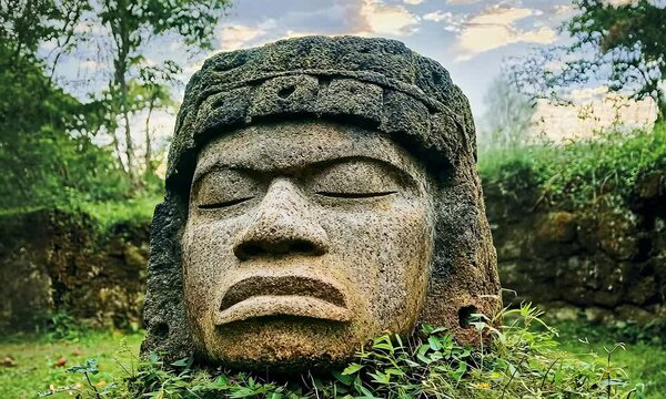 Giant Olmec head sculpture in jungle, travel and culture concept