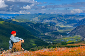 Naklejka premium Male traveler with backpack enjoying stunning mountains and winding river view
