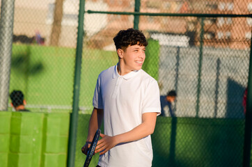 Young tennis player holding racket and smiling on court
