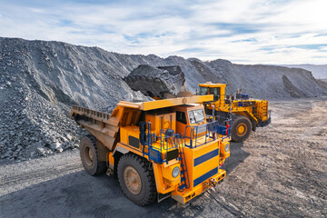 Aerial view excavator loads gold ore rock formation into back of heavy mining dump truck. Concept open pit coal mine © Parilov