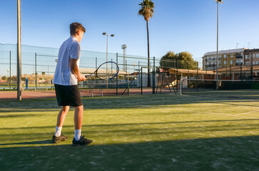 Young tennis player preparing to serve on a sunny day