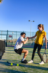 Young tennis players doing squats and holding hands on court