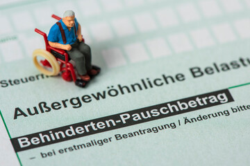 Auf einem Steuerformular über außergewöhnliche Belastungen für das Finanzamt steht ein Modell-Rollstuhl © Wolfilser