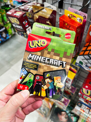 Naklejka premium Kyiv, Ukraine - February 09, 2025: Hand holding a Minecraft themed Uno card pack displayed in a store