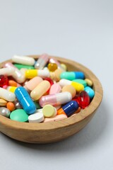 Various pills in a bowl on gray background