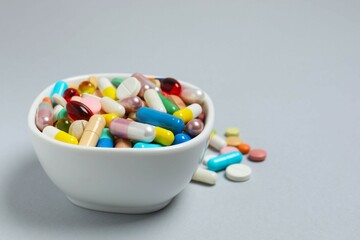 Various pills in a bowl on gray background