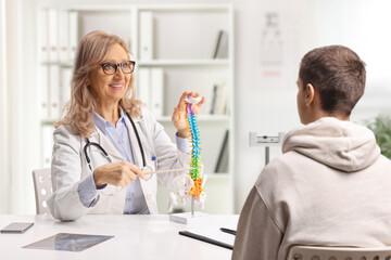 Fototapeta premium Doctor at the office talking to a male patient and showing a human spine model
