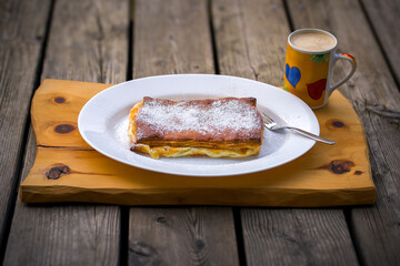 ready to eat - puff pastry, quark strudel, warm curd cheese strudel a austrian dish, served on a white plate on a wood board