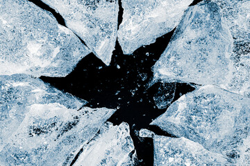 Broken ice. Crushed textured ice with cracks on a black background, close-up.
