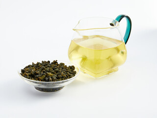 dry Chinese tea in a plate and next to it brewed in a teapot, photo on a white background