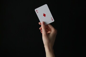 Woman with playing card against black background, closeup