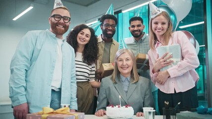 People surrounding their beloved director. Preparing for congratulating respectable person at work with birthday. Holding gifts. Balloons in background. Looking at camera while smiling.