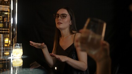 Focusing on beautiful woman in soda drink accompanied by friends at luxurious bar nightclub. Smart bartender providing excellent service beverage menu at vibrant nightlife party atmosphere. Vinosity.