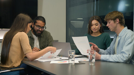 Diverse businessmen businesswomen team review sales data documents paperwork teamwork discussion multiracial business men women colleagues coworkers company brainstorm talk at table in conference room