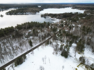 Aerial drone over Trafalgar Bay, Gaunt Bay and Moon River Road in rural cottage country Bala, in the Muskoka Lakes area of Ontario, Canada. Pine trees and snow during a cold winter day.