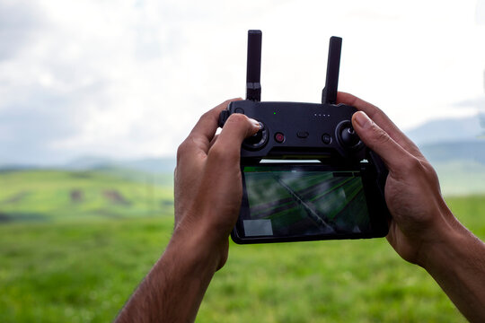 Male hands holding generic design dron remote controller doing some setings ready to run it into the sky.