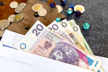 Polish zloty banknotes in an envelope with coins and dice