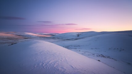A serene winter landscape at twilight, showcasing gently rolling snow-covered hills under a pastel sky.