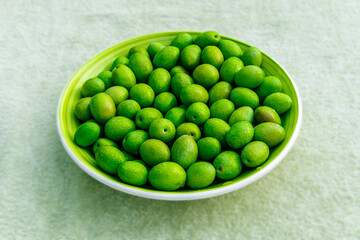 Beautiful kitchen plate with fresh green olives on monochrome green salad background. Olive dish closeup, foor and drink concept
