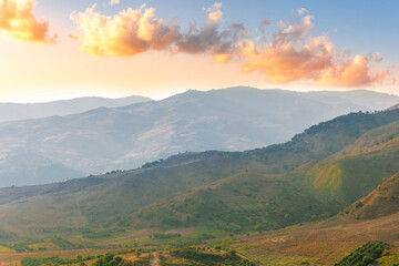 Naklejka premium scenic rustic landscape with green hills and farms in a mountain valley during colorful cloudy sunset