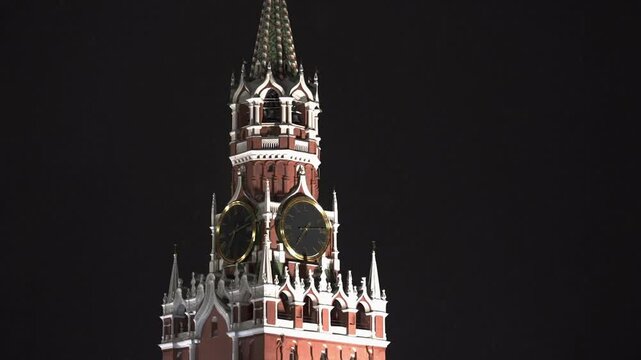 Moscow January 08 2021, Winter night enveloped Red Square and Moscow, in spotlight - majestic Spasskaya Tower of Kremlin. Her famous chimes, decorated with garlands of festive lights, sparkle in dark.