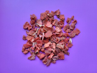 Dried portion of carrot flakes on a violet background.