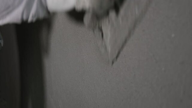 Worker smoothing plaster on a wall, Close-up of a worker using a plastering tool to smooth a wall surface.