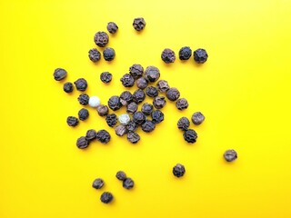 Aromatic pile of pepper seeds on a yellow background.
