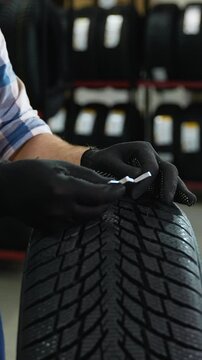 Tire store worker checking tread depth with gauge