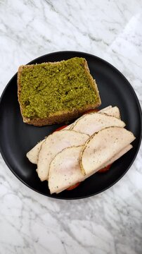 Making a pesto and turkey ham sandwich