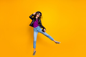 Full size photo of crazy funky gilr jump enjoy walk weekend wear good look outfit denim jeans isolated over yellow color background