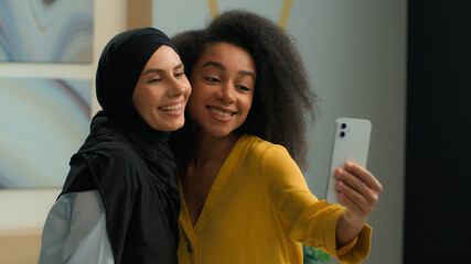 Diverse multiethnic Muslim hijab African American business women businesswomen office colleagues female friends happy cheerful girls ladies models posing smile mobile phone camera photo selfie trend