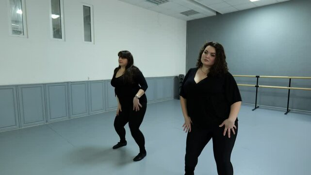 Two fat women dancing in a dance hall. Women in black clothes