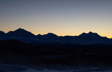 Orange sky behind mountain range in Alaska