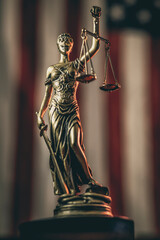 Lady Justice figure holding scales in front of American flag