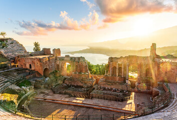 Panoramic view of a beautiful sunset in Ancient Theatre of Taormina in Sicily with antique italian town and mountain sunset on background. Holidays and sightseeing in Italy