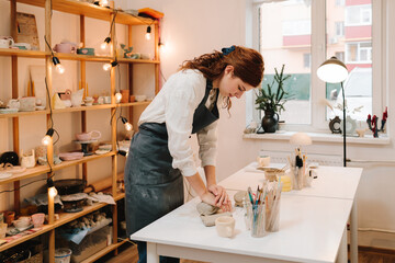 Female artisan molds piece of clay in the art studio. Sculpting clay for making earthenware.