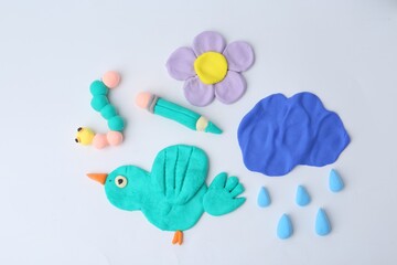 Different colorful child's crafts made of play dough on grey background, flat lay