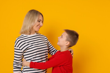 Mother and son hugging on orange background
