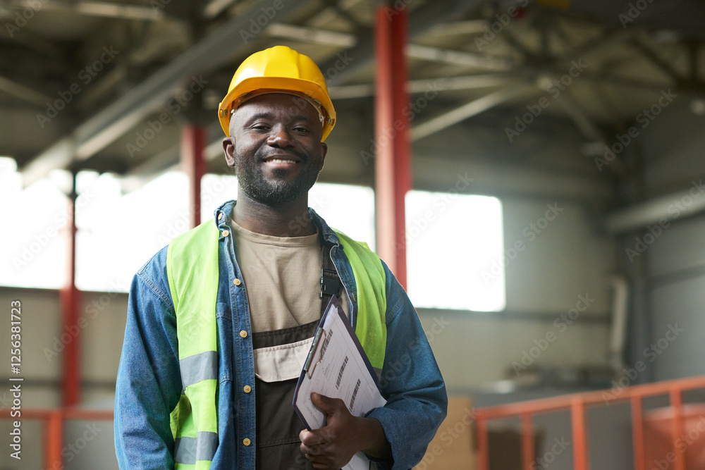 Leinwandbilder young successful factory worker with document in hand looking at camera while working in spacious wa