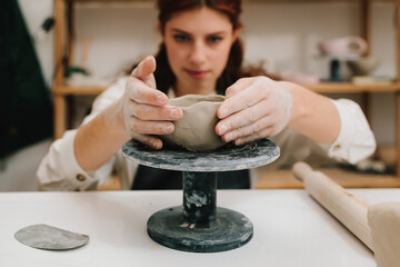 Process of creating ceramic products. Female potter hands shows ceramic bowl ready for firing in a...