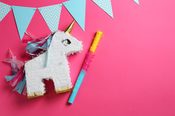 Bright pinata in shape of unicorn and party accessories on pink background, top view. Space for text