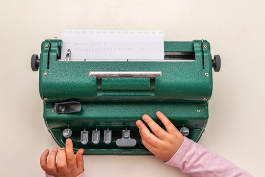 Typing on a braille machine. Children's hands on the machine in close-up. Training of blind people. Learning to write.