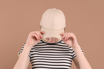 Woman in stylish baseball cap on beige background. Mockup for design