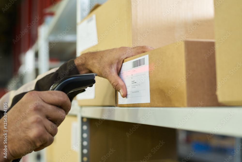Leinwandbilder Hand of modern engineer scanning barcodes on stickers on packed cardboard boxes standing on shelf in warehouse