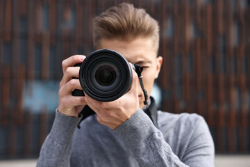 Professional photographer taking picture with camera outdoors, selective focus