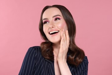 Portrait of beautiful young woman with stylish makeup and gorgeous hair on pink background